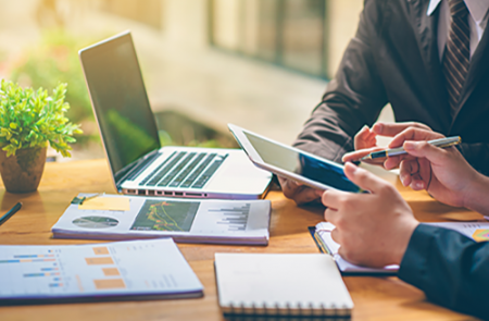 Business people collaborating using laptops and tablets on desk